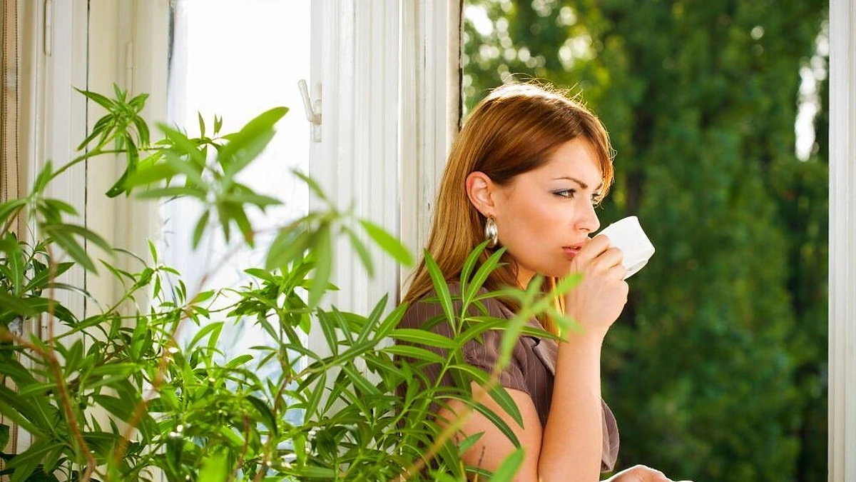 Moteris terasoje tarp augalų