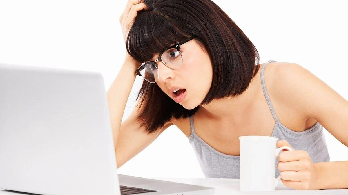 Mergina sėdinti prie kompiuterio ir gerianti kavą