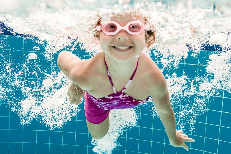 Mergaitė plaukioja baseine.