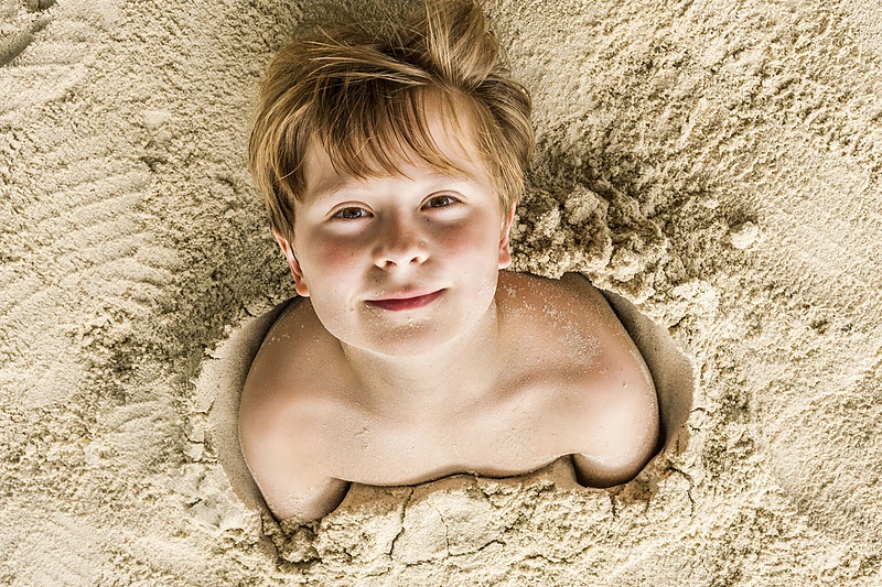 Smėliu užsikasęs berniukas