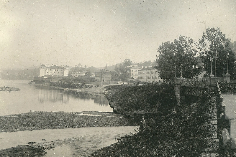 Už tilto per Vilnią matyti du kareivinių korpusai. Pirmasis – dabartinių Istorijų namų pastatas (1905 m.) / Fotografas Tiburcijus Chodzka. Lietuvos nacionalinis muziejus